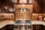 This stunning kitchen boasts a custom copper range hood, granite countertops, and rich dark wood cabinetry.