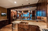 This luxurious kitchen boasts a stunning copper farmhouse sink, granite countertops, and custom dark wood cabinetry.