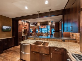 This luxurious kitchen boasts a stunning copper farmhouse sink, granite countertops, and custom dark wood cabinetry.