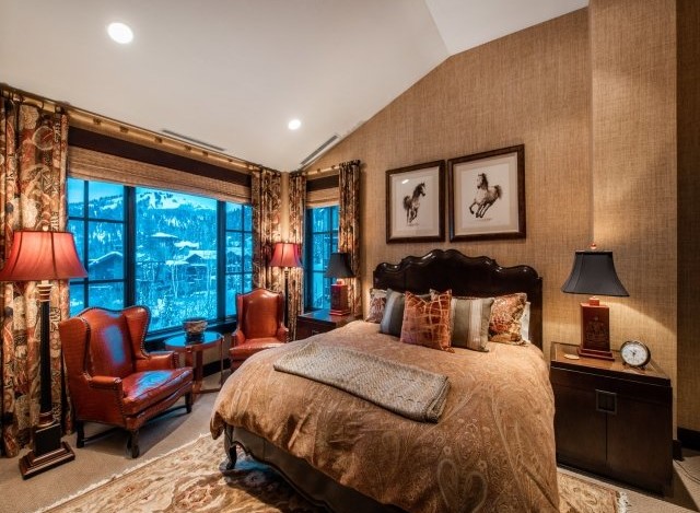 Luxurious mountain-view bedroom with a king-size bed, leather armchairs, and stunning window views.