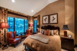 Luxurious mountain-view bedroom with a king-size bed, leather armchairs, and stunning window views.