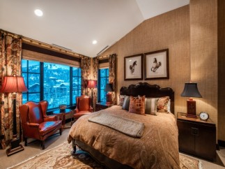 Luxurious mountain-view bedroom with a king-size bed, leather armchairs, and stunning window views.