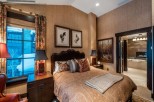 Luxurious bedroom with a king-size bed, featuring an ensuite bathroom with a soaking tub and fireplace.
