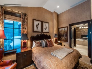 Luxurious bedroom with a king-size bed, featuring an ensuite bathroom with a soaking tub and fireplace.