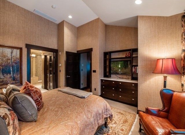 Luxurious master bedroom with a king-size bed, ensuite bathroom, and a built-in entertainment center.