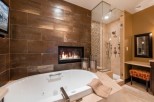 Indulge in luxury with this stunning bathroom featuring a spacious soaking tub, a cozy fireplace, and a walk-in shower with multiple shower heads.
