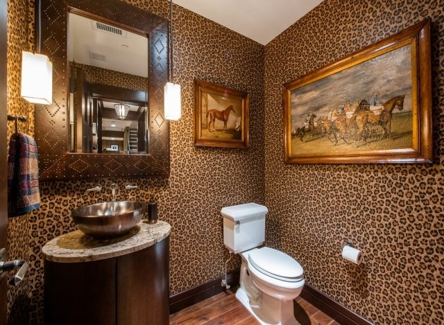This luxurious powder room boasts a stunning leopard-print wallpaper, creating a bold and chic atmosphere.