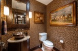 This luxurious powder room boasts a stunning leopard-print wallpaper, creating a bold and chic atmosphere.