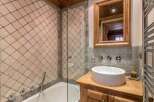 Discover the charm of this bathroom, featuring a unique tiled wall design and a stylish wooden vanity.