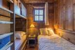This cozy bedroom features rustic wooden walls and a charming bunk bed, perfect for a mountain getaway.