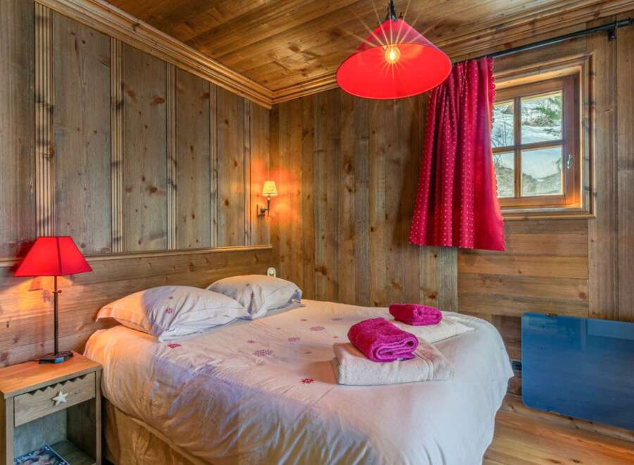 Cozy bedroom with wooden walls and ceiling, creating a warm and inviting atmosphere.
