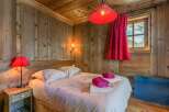 Cozy bedroom with wooden walls and ceiling, creating a warm and inviting atmosphere.