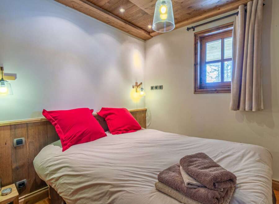 This cozy bedroom features a comfortable bed with vibrant red pillows, creating a warm and inviting atmosphere.