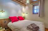 This cozy bedroom features a comfortable bed with vibrant red pillows, creating a warm and inviting atmosphere.