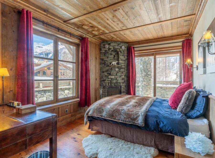 Experience the charm of this cozy bedroom, featuring a rustic stone fireplace and wooden accents throughout.