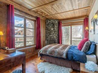 Experience the charm of this cozy bedroom, featuring a rustic stone fireplace and wooden accents throughout.