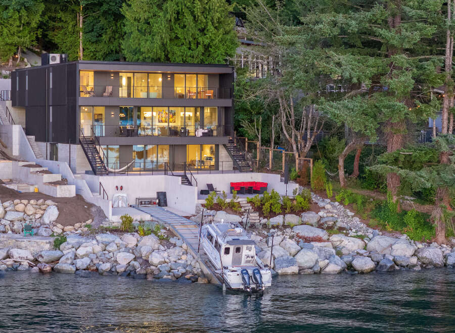 This stunning waterfront property boasts a modern, multi-story home with expansive windows offering breathtaking views.