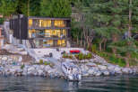 This stunning waterfront property boasts a modern, multi-story home with expansive windows offering breathtaking views.