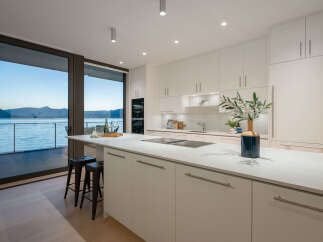 This stunning kitchen boasts a modern design with sleek white cabinetry and a spacious island, perfect for culinary creations and entertaining.