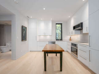 This modern kitchen boasts sleek white cabinetry, offering ample storage and a clean aesthetic.