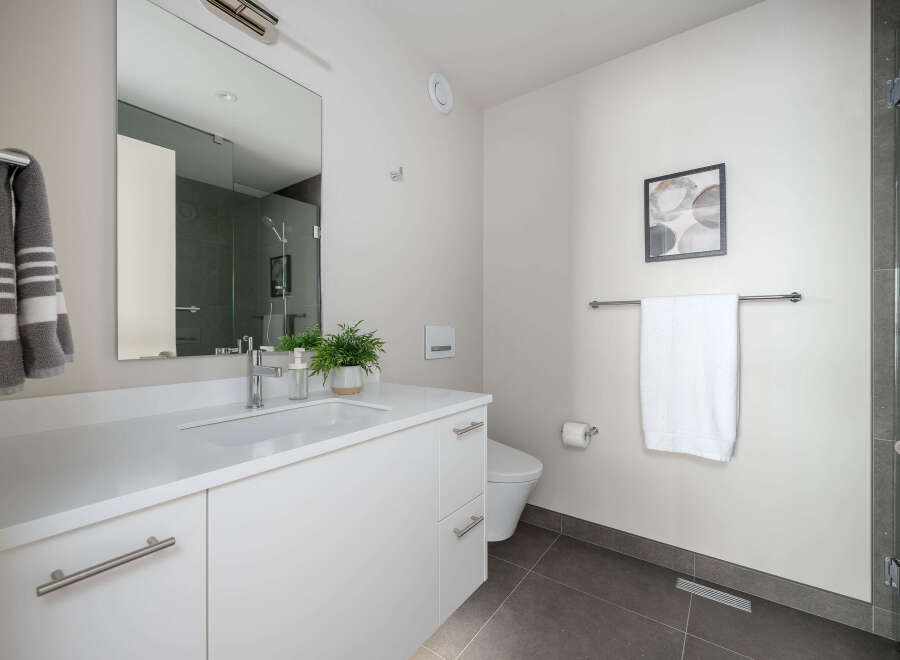 This modern bathroom boasts a sleek, minimalist design with a pristine white vanity and a large mirror.