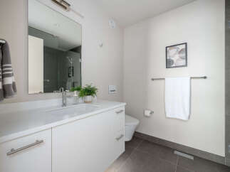 This modern bathroom boasts a sleek, minimalist design with a pristine white vanity and a large mirror.