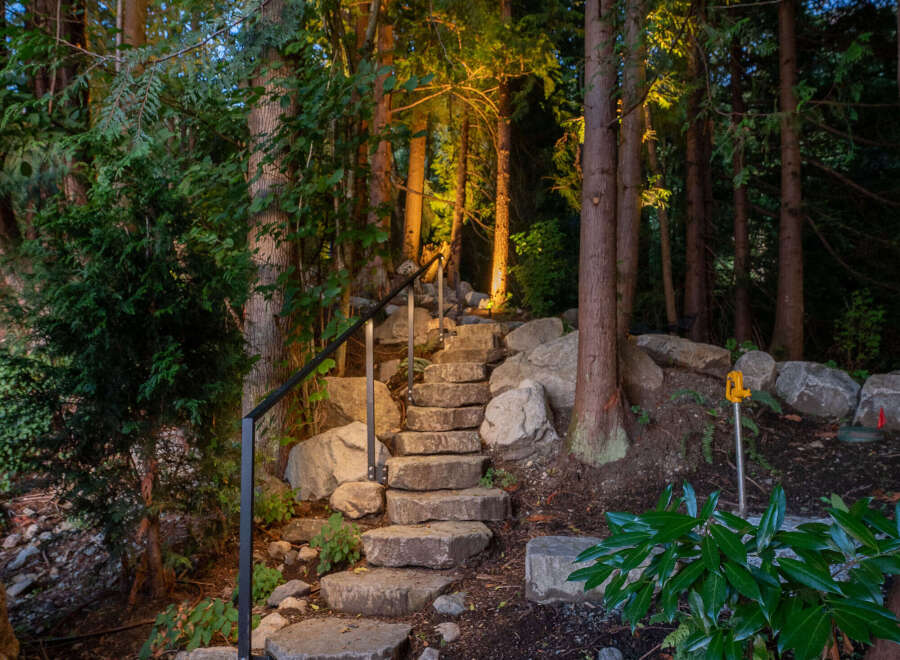 Discover a serene retreat with this stunning property featuring a stone staircase that leads you through a lush, wooded landscape.