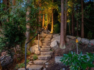 Discover a serene retreat with this stunning property featuring a stone staircase that leads you through a lush, wooded landscape.
