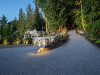 Discover the allure of this stunning property, featuring a beautifully illuminated gravel driveway that leads to a private oasis.