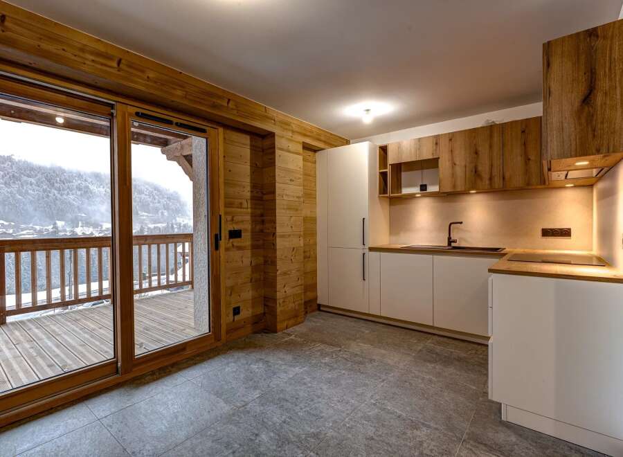 This stunning property features a modern kitchen with sleek white cabinetry and warm wooden accents.