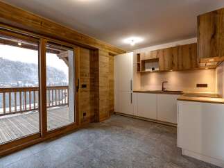 This stunning property features a modern kitchen with sleek white cabinetry and warm wooden accents.