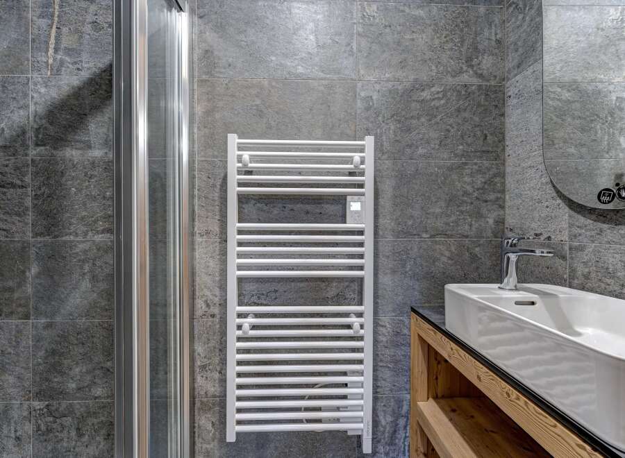 This modern bathroom features a sleek design with a heated towel rack, a glass shower door, and a stylish sink.