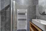 This modern bathroom features a sleek design with a heated towel rack, a glass shower door, and a stylish sink.