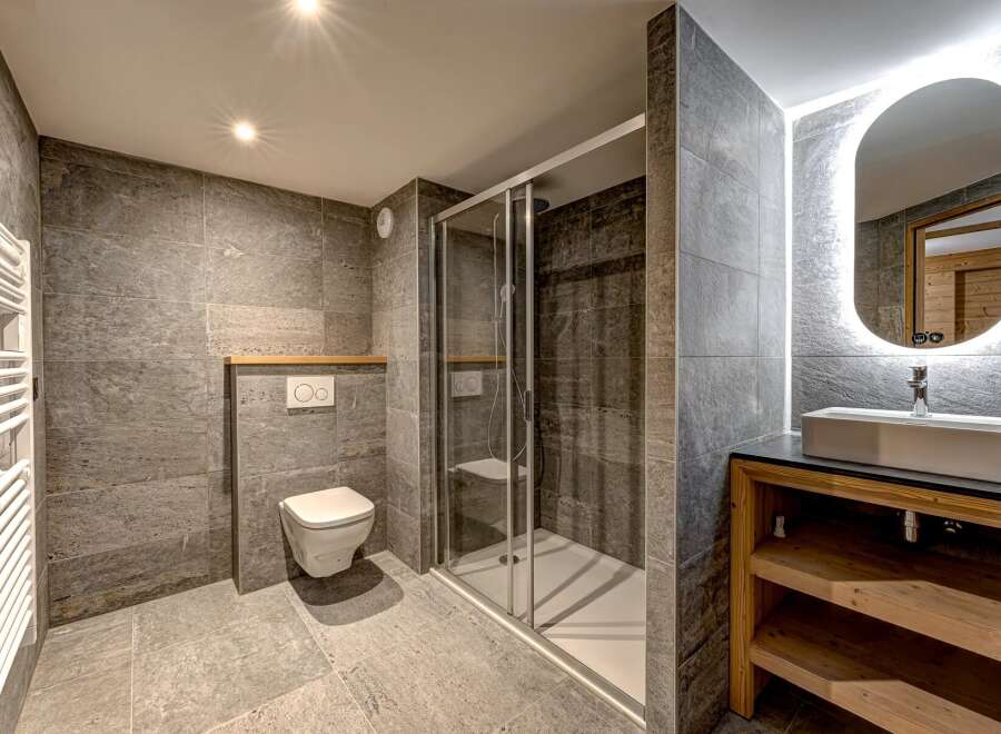 This modern bathroom features a sleek design with gray tiled walls and flooring, creating a sophisticated and contemporary ambiance.