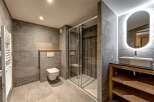 This modern bathroom features a sleek design with gray tiled walls and flooring, creating a sophisticated and contemporary ambiance.