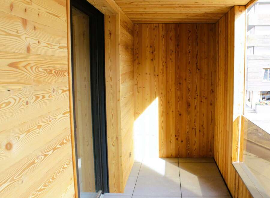 Step into this inviting balcony, showcasing a warm embrace of natural wood paneling.