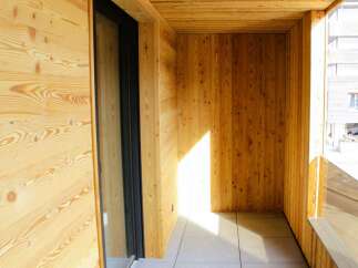 Step into this inviting balcony, showcasing a warm embrace of natural wood paneling.