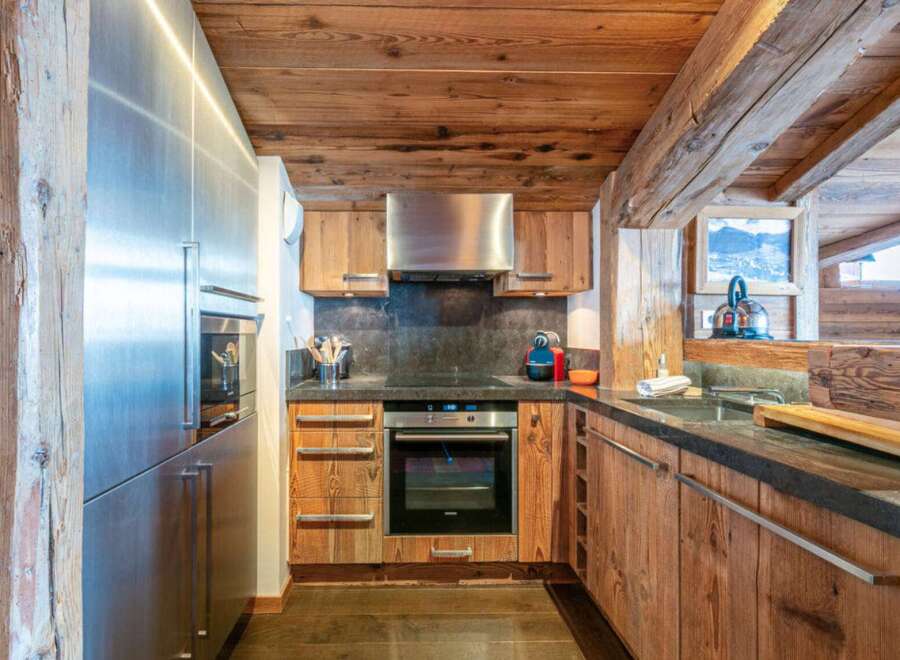 This stunning kitchen boasts a rustic charm with its wooden cabinets and ceiling, creating a warm and inviting atmosphere.