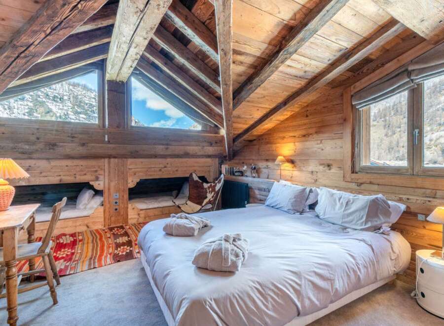 Experience the charm of this cozy chalet bedroom, featuring a rustic wooden interior and a stunning mountain view.