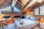 Experience the charm of this cozy chalet bedroom, featuring a rustic wooden interior and a stunning mountain view.