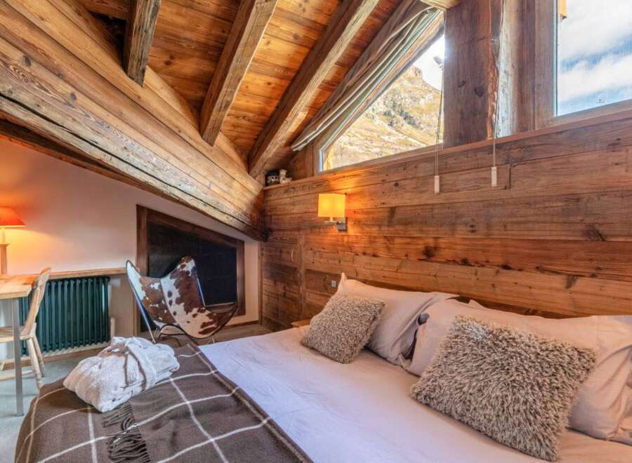 Experience the rustic charm of this stunning bedroom, featuring exposed wooden beams and a cozy ambiance.