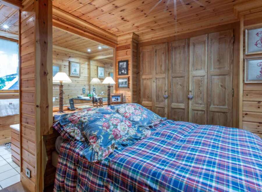 This cozy bedroom features a warm, inviting ambiance with its wooden walls and ceiling.