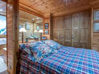 This cozy bedroom features a warm, inviting ambiance with its wooden walls and ceiling.