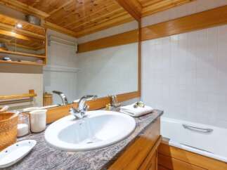 This cozy bathroom features a beautiful wooden ceiling and cabinetry, creating a warm and inviting atmosphere.