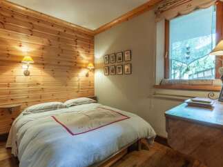 Cozy bedroom with wood paneling and a comfortable bed.