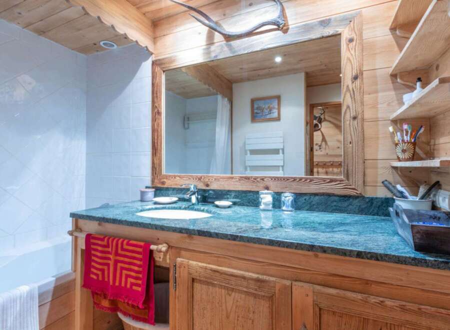This charming bathroom features a rustic wooden vanity with a marble countertop, offering a touch of elegance.