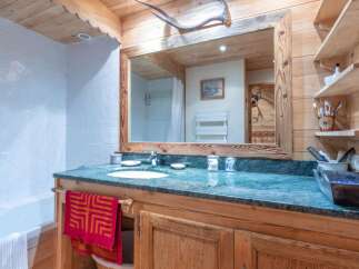 This charming bathroom features a rustic wooden vanity with a marble countertop, offering a touch of elegance.