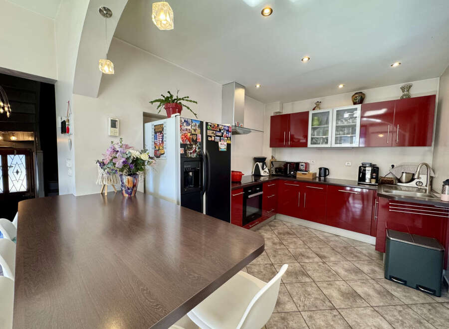 This stunning kitchen boasts modern design with sleek red cabinetry and stainless steel appliances.