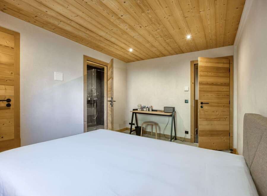 This cozy bedroom features a beautiful wooden ceiling and doors, creating a warm and inviting atmosphere.