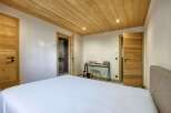 This cozy bedroom features a beautiful wooden ceiling and doors, creating a warm and inviting atmosphere.